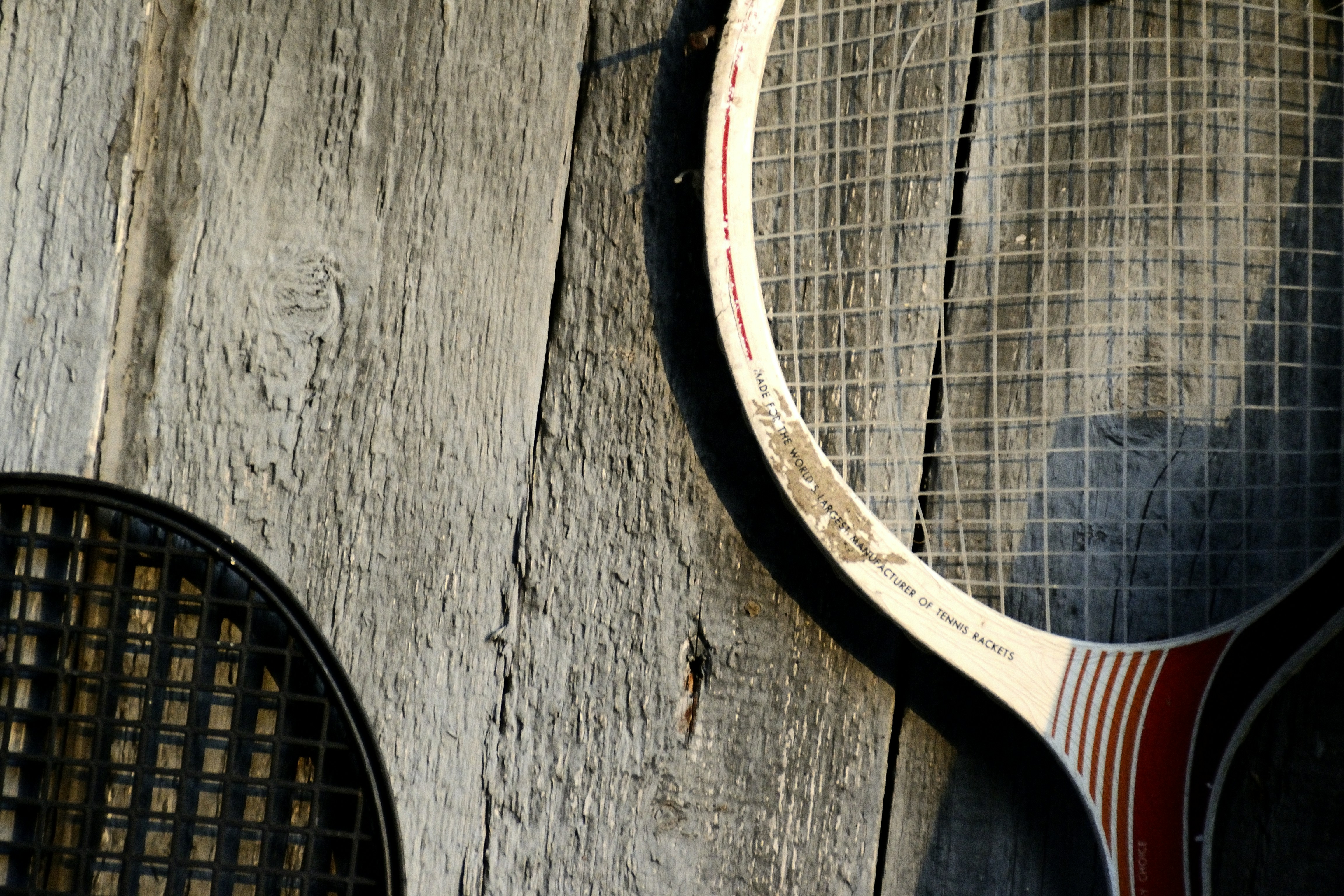 Two vintage tennis racquets leaning against a wooden wall.