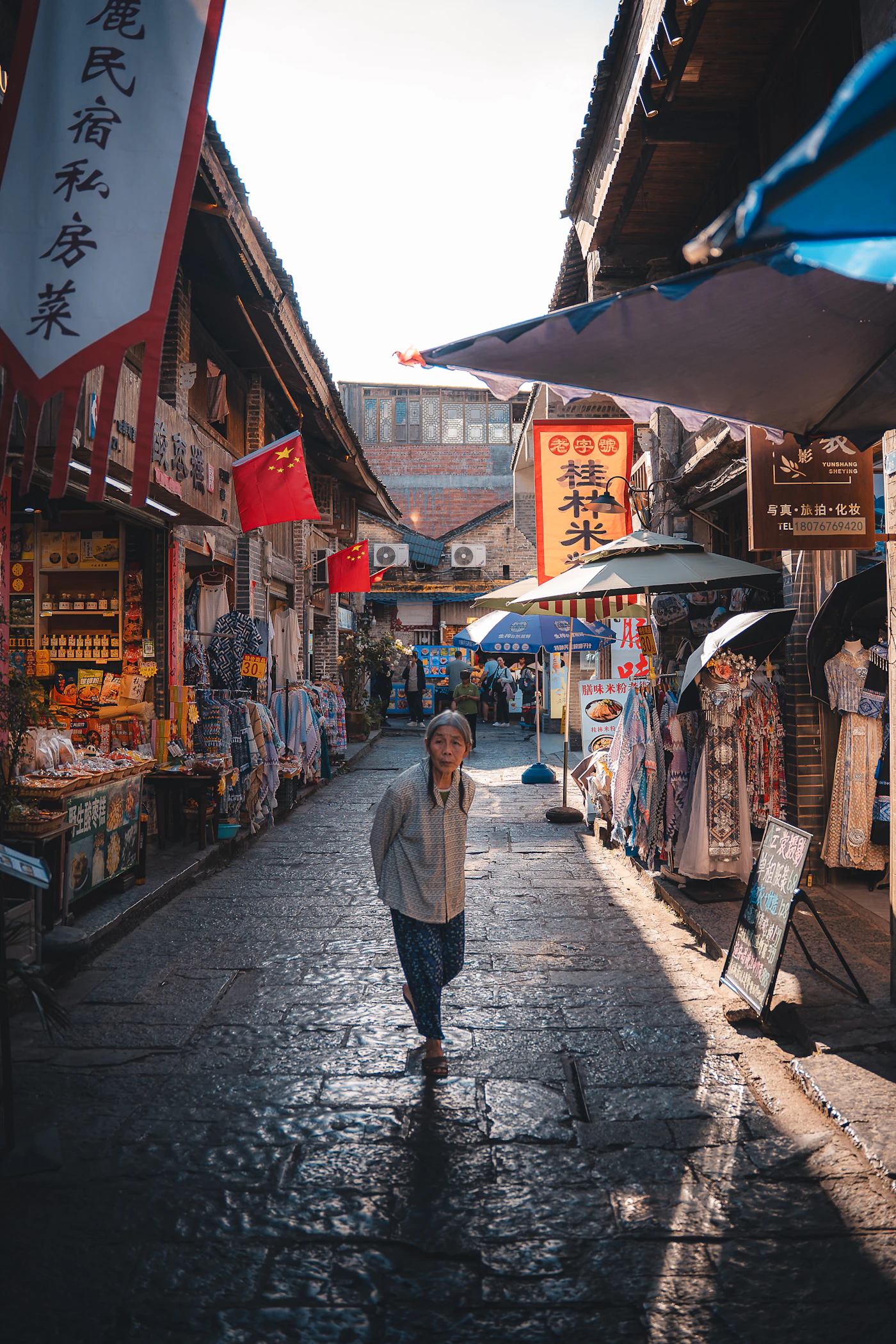 A person walking along a cobblestone market street