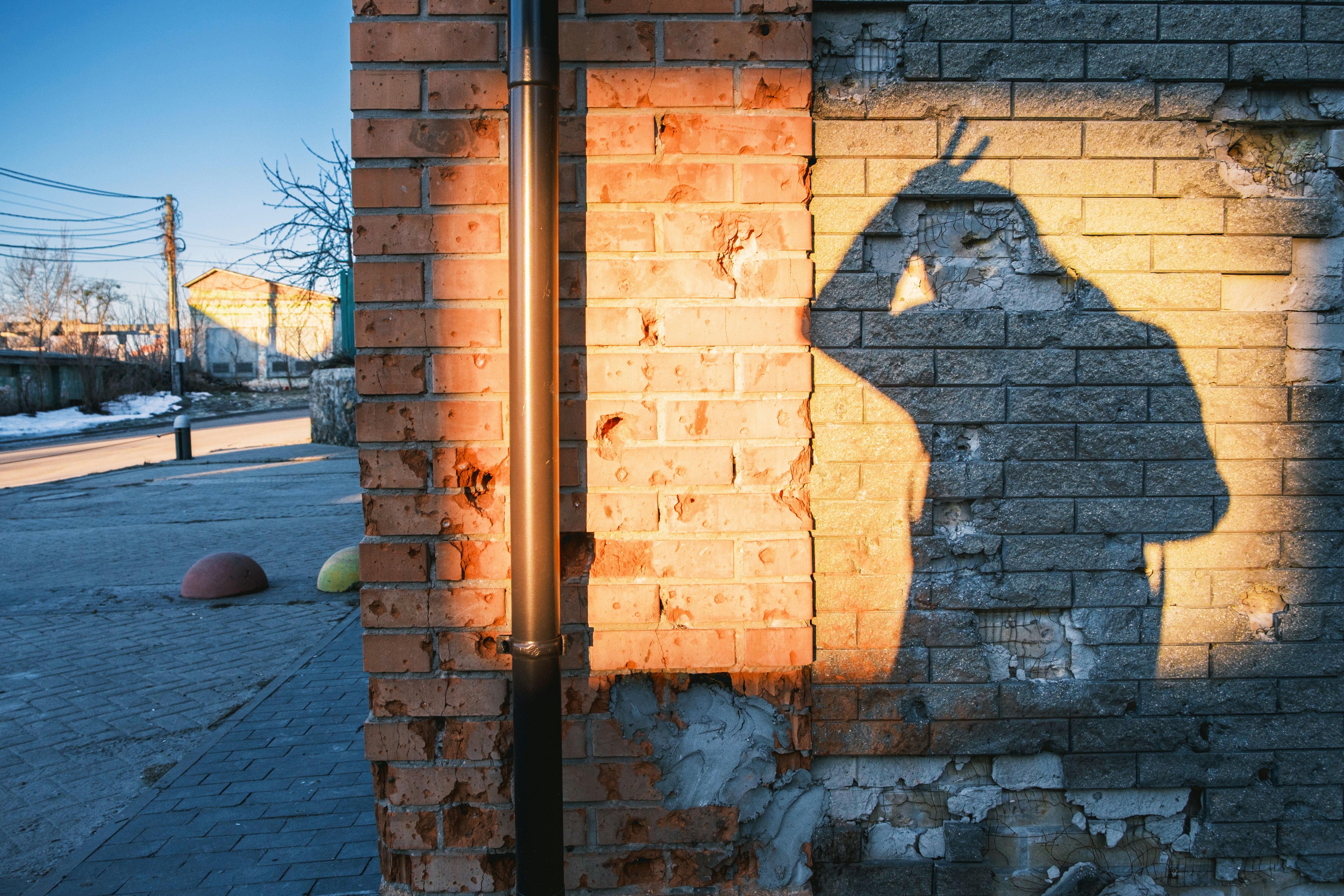 Shadow of a person making peace sign on brick wall.