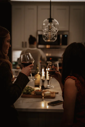 Friends toasting with wine at a kitchen counter.