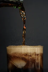 Cola pouring into a glass with ice