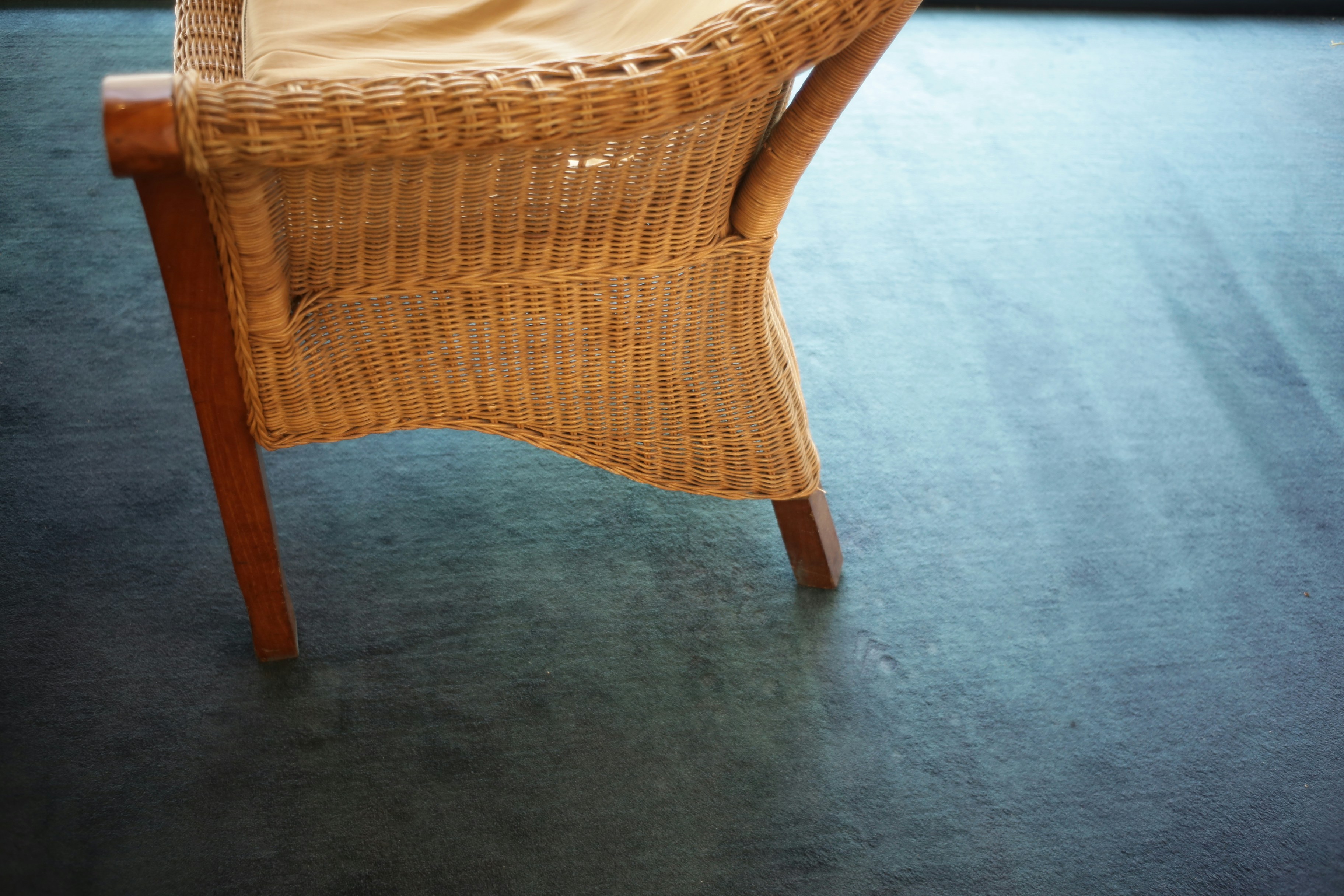 Wicker chair with wooden legs on a dark floor