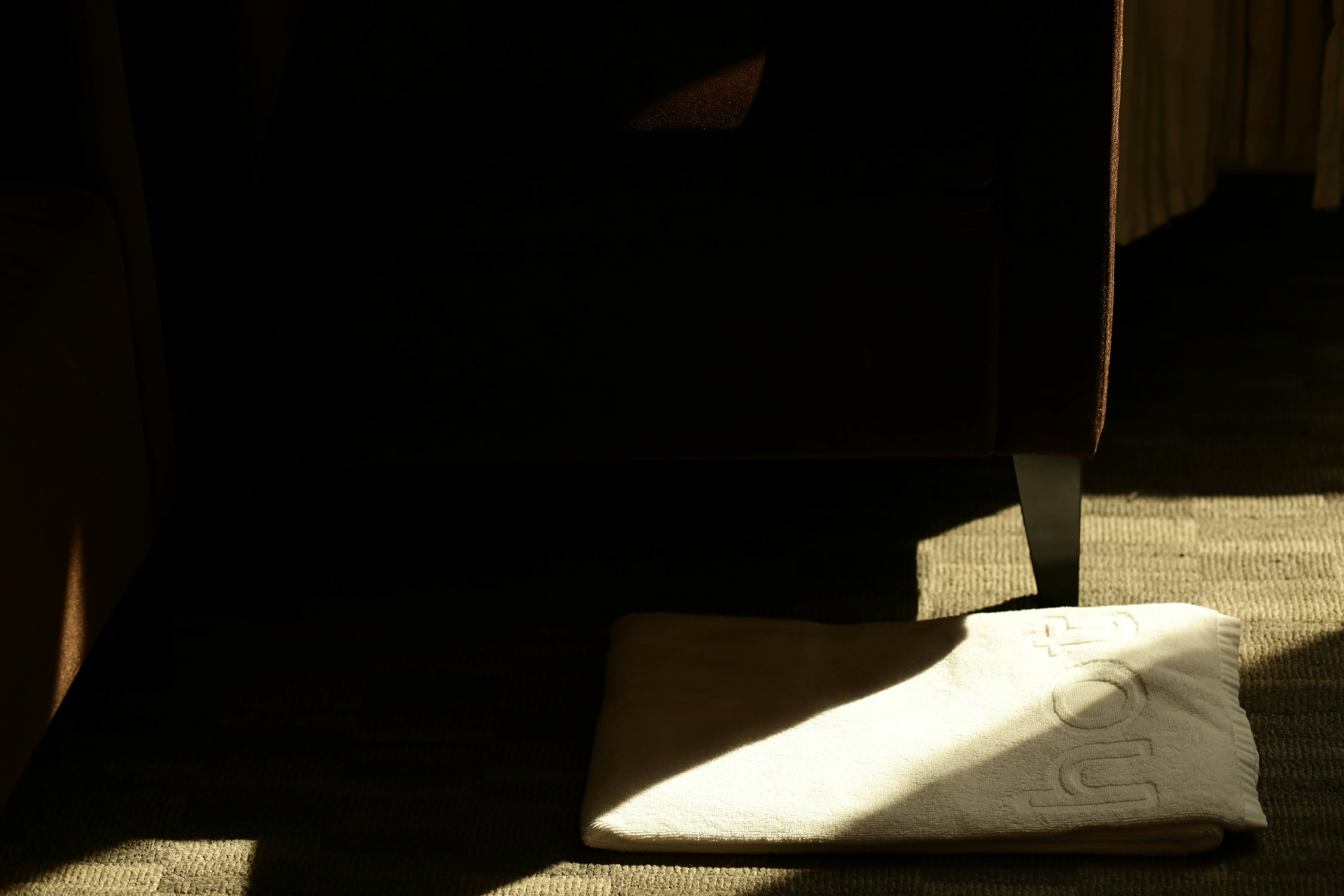 A white shoe rests on a textured surface in shadow.