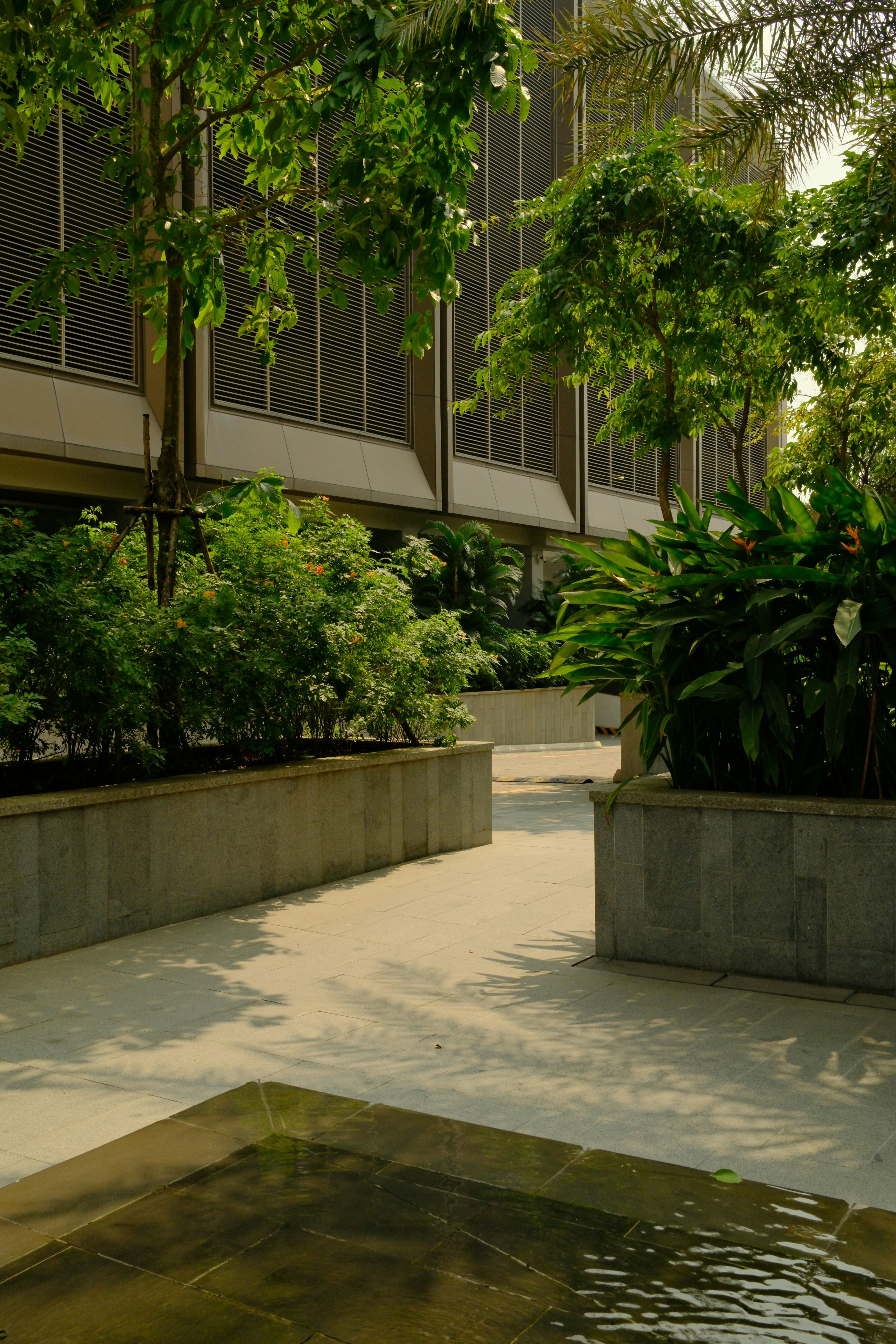 Modern building with lush green landscaping and water feature.