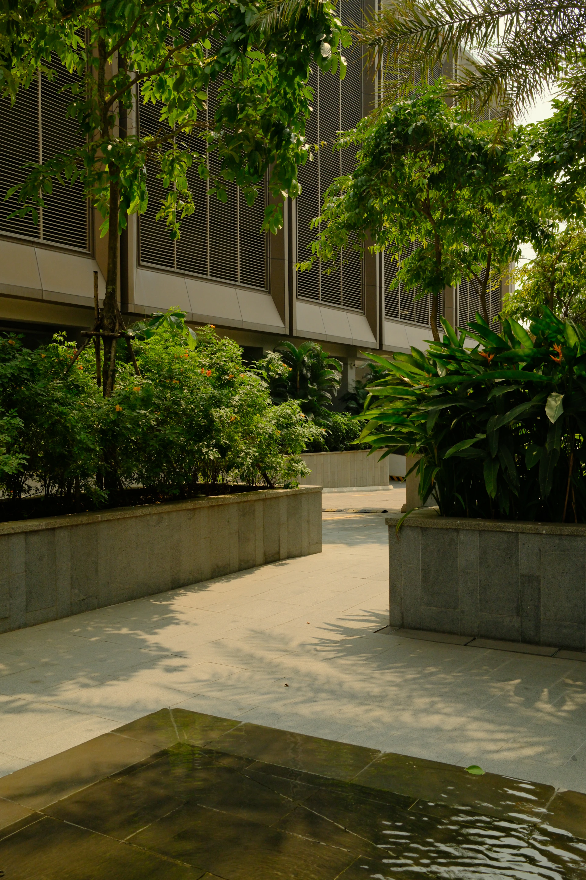 Modern building with lush green landscaping and water feature.