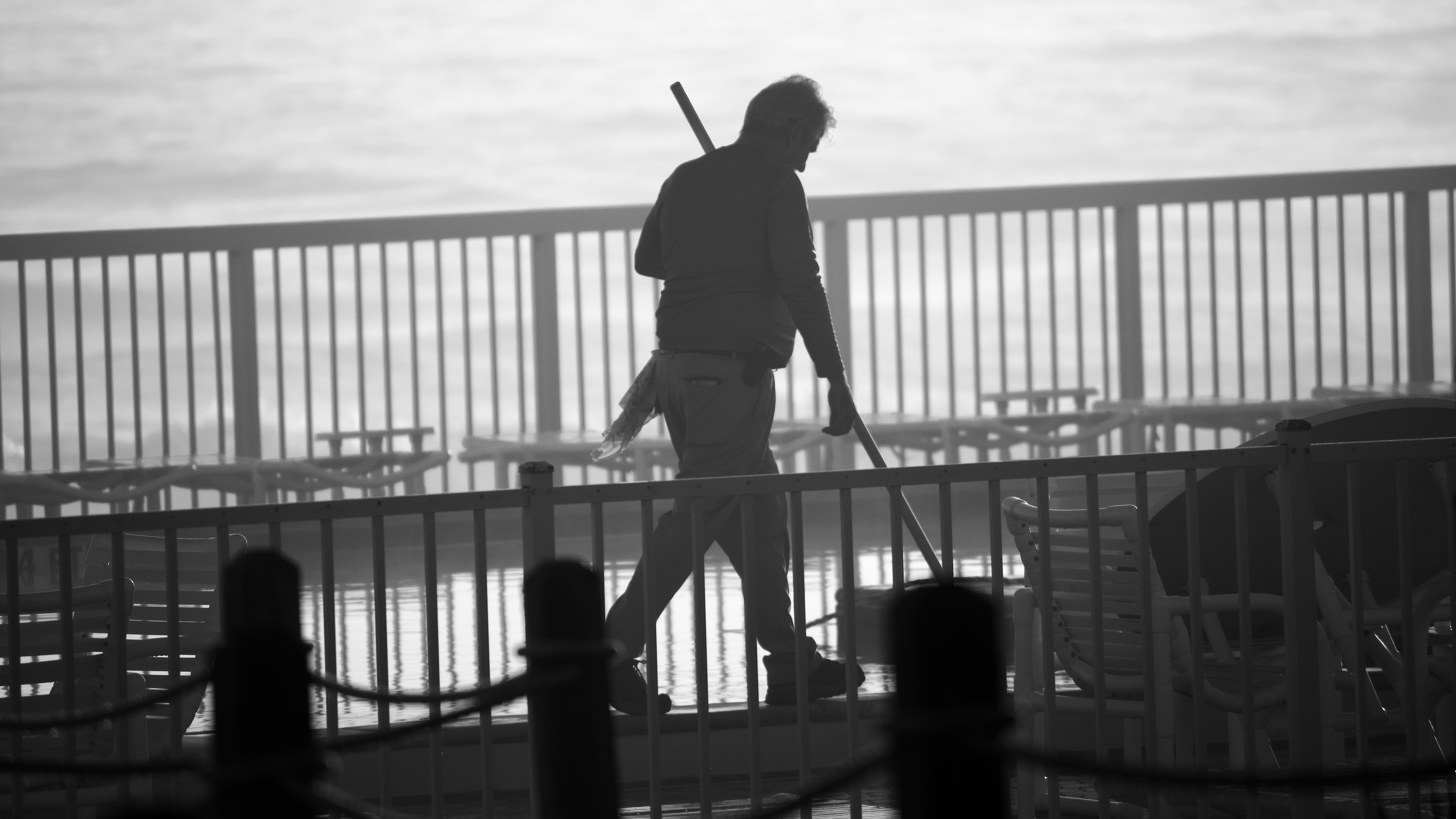 Silhouette of a person walking along a railing