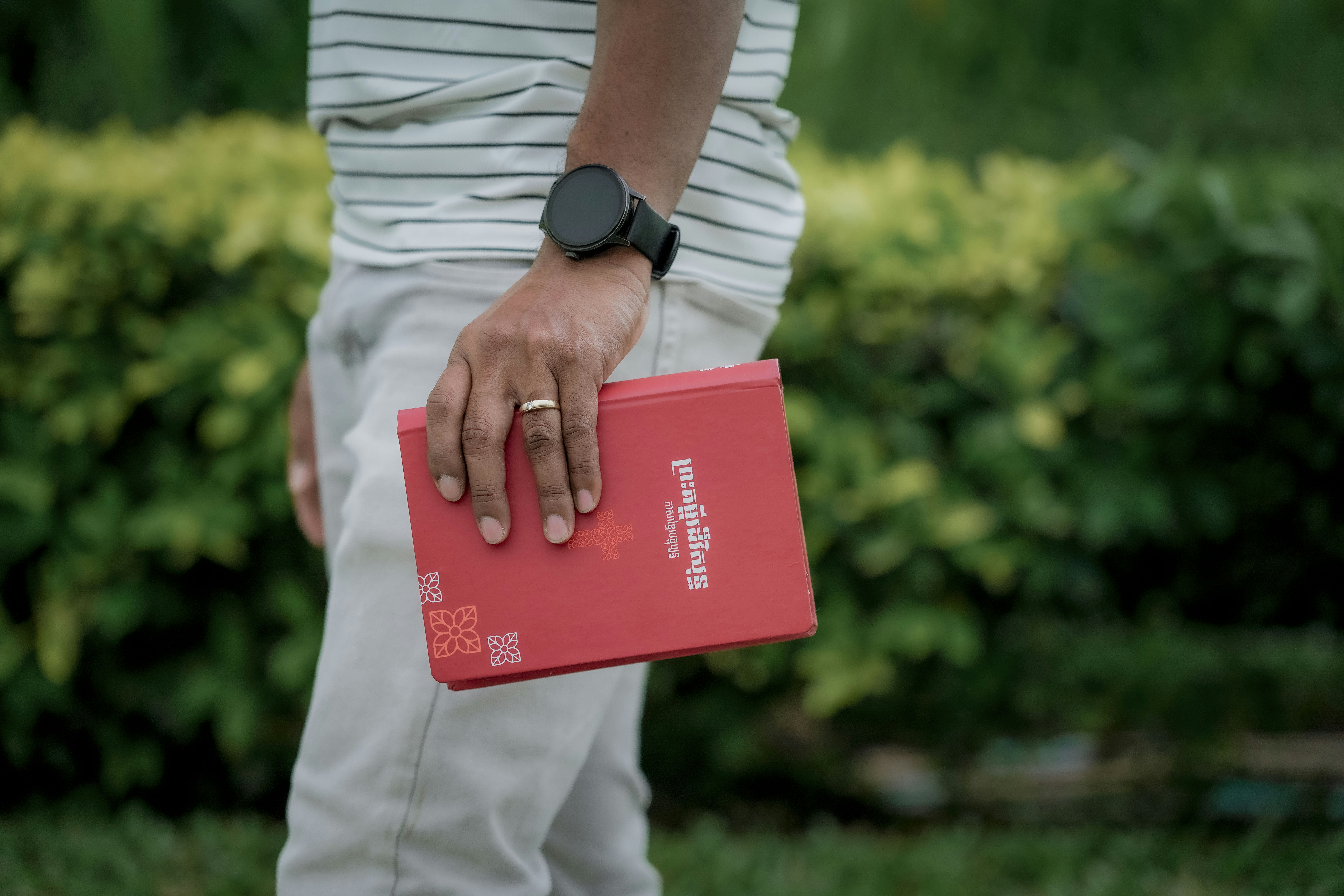 Person, die ein rotes Buch mit einer Uhr hält