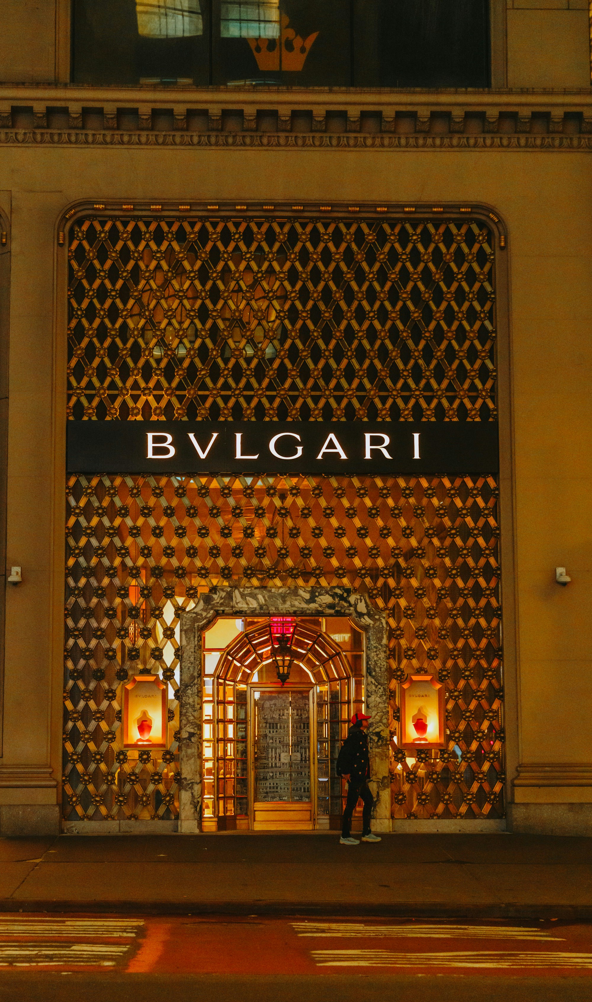La entrada de la tienda Bulgari por la noche con detalles dorados ornamentados.
