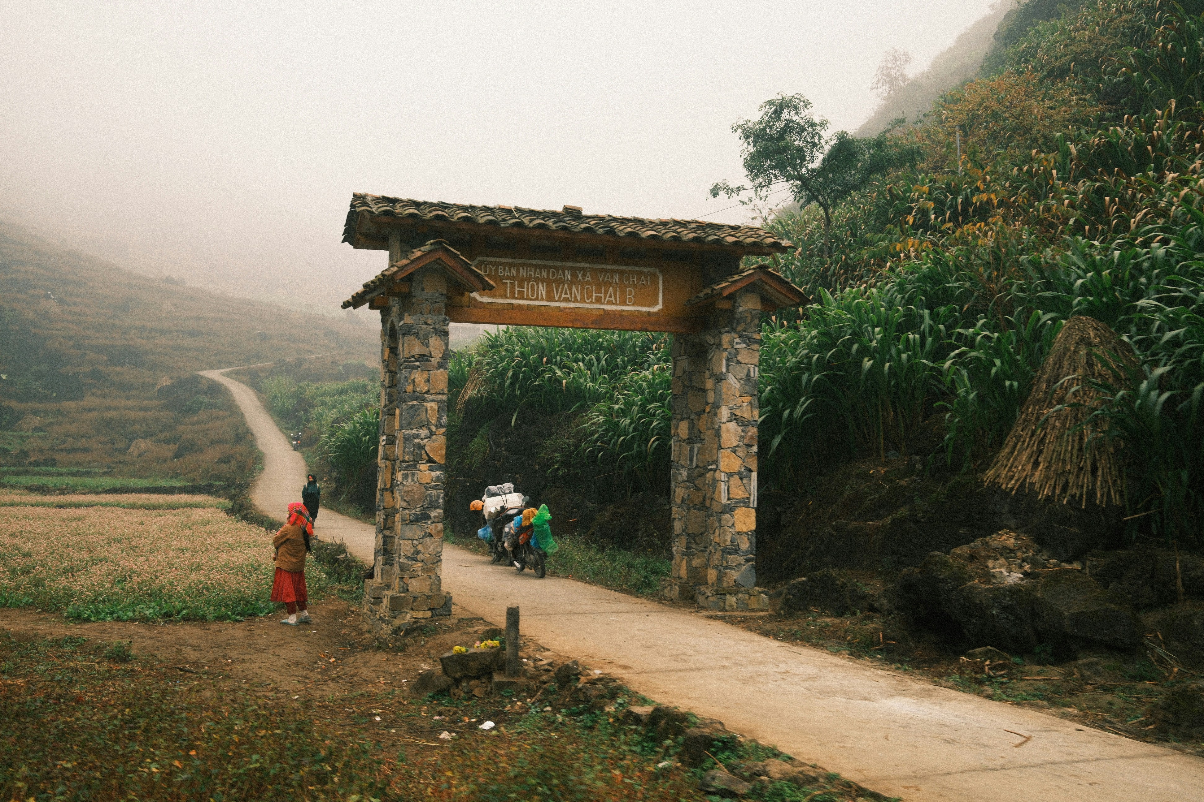 Steinbogen über eine Landstraße mit nebligen Bergen.