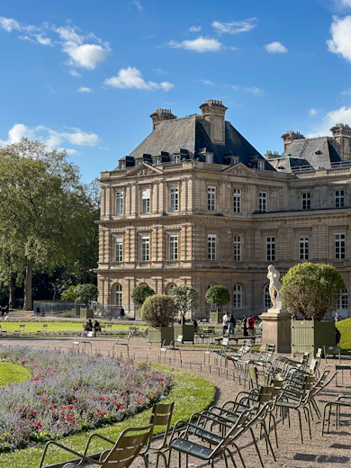 Grand building in a park with chairs and flowers.
