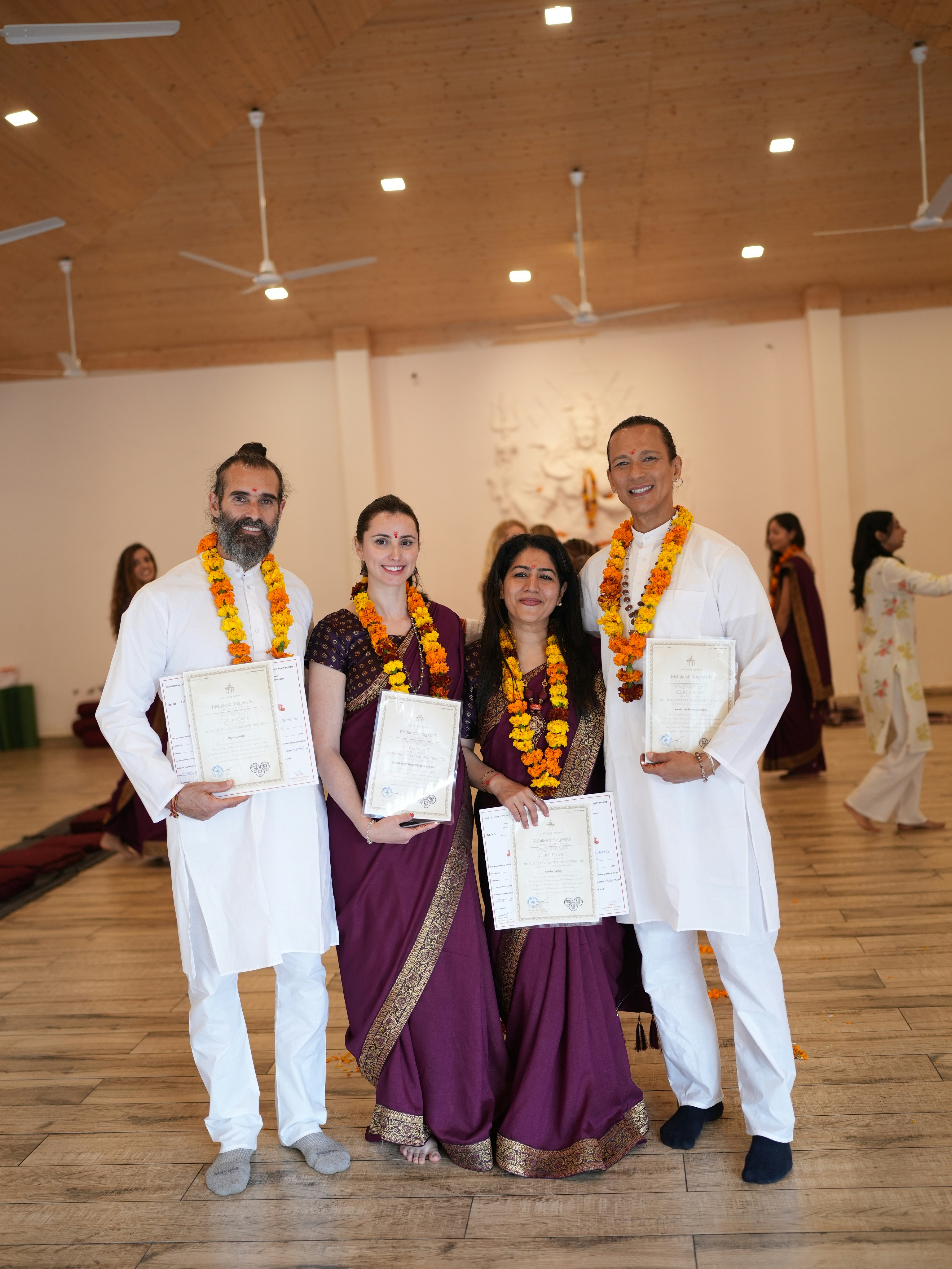 Four people in traditional indian attire holding certificates