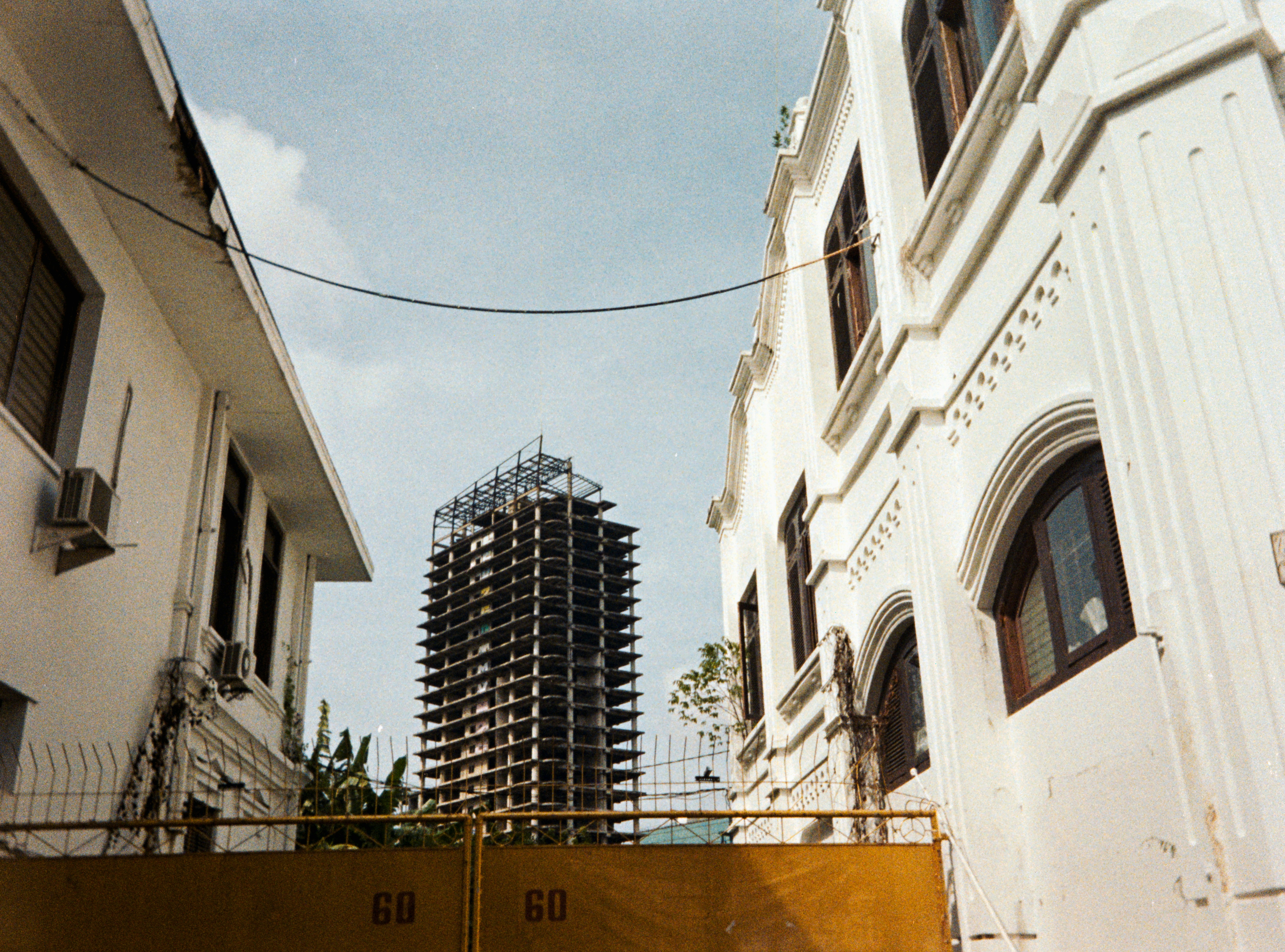 Tall unfinished building between white structures