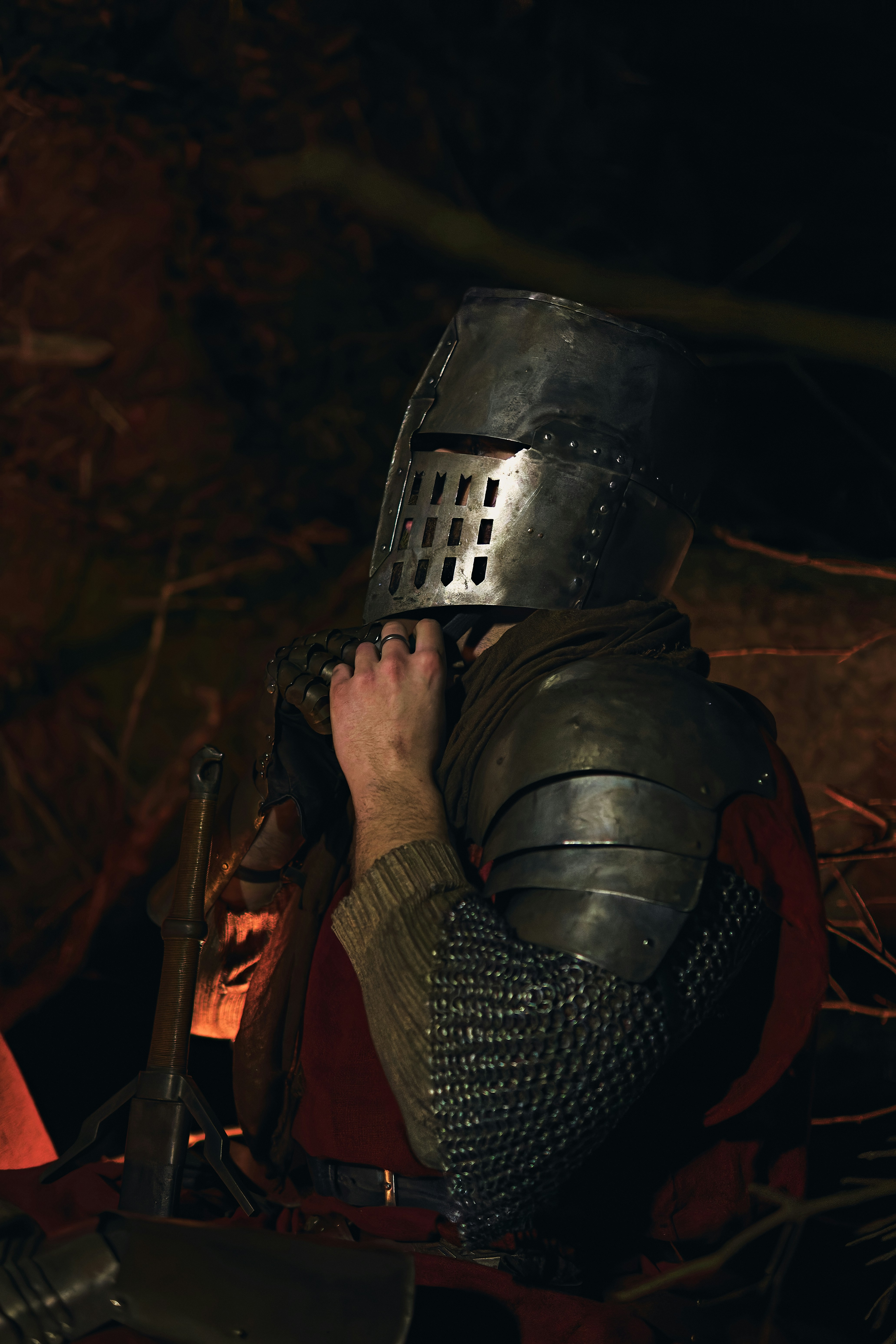 Knight in armor adjusting helmet in dark setting