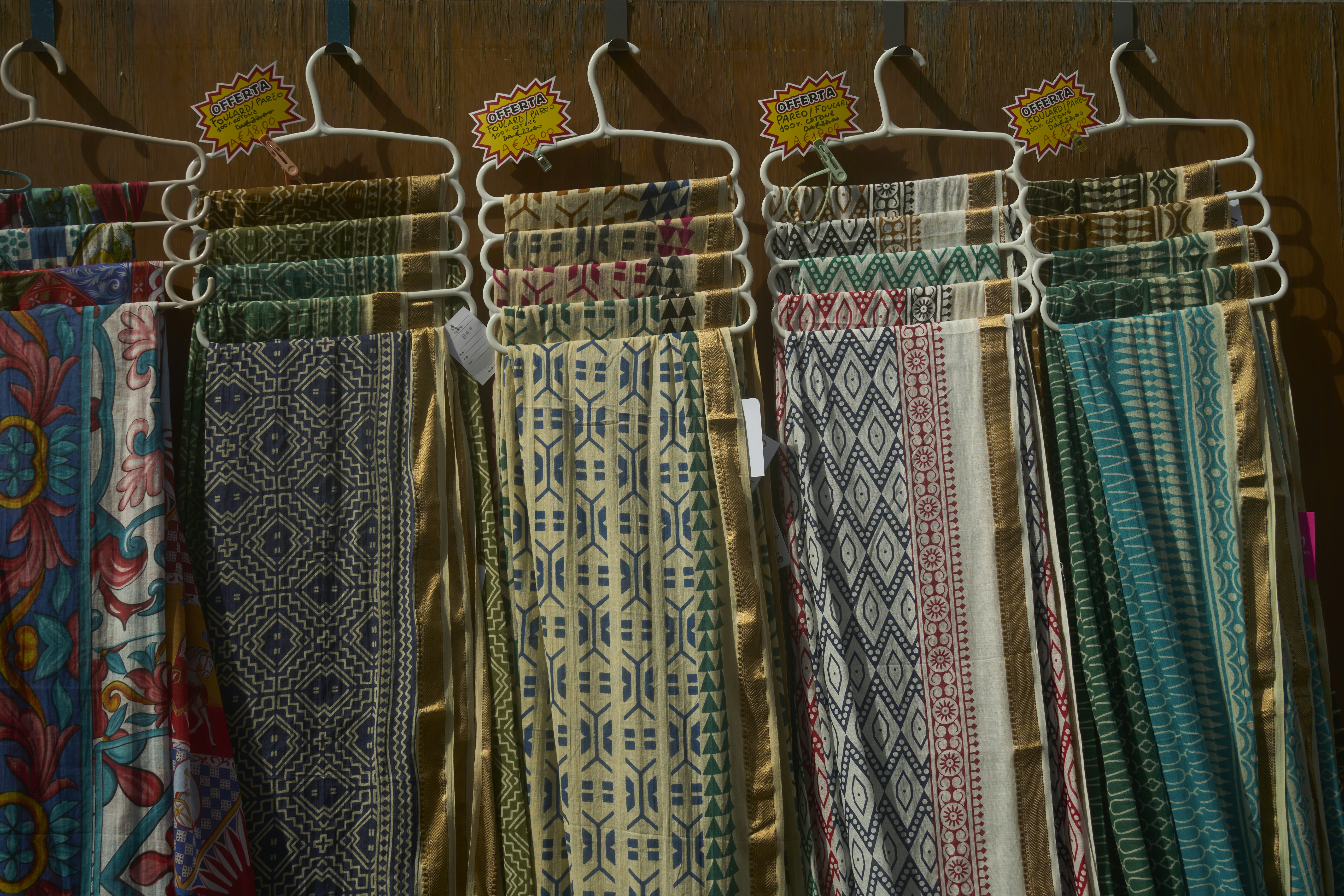 Colorful textiles with intricate patterns displayed on hangers