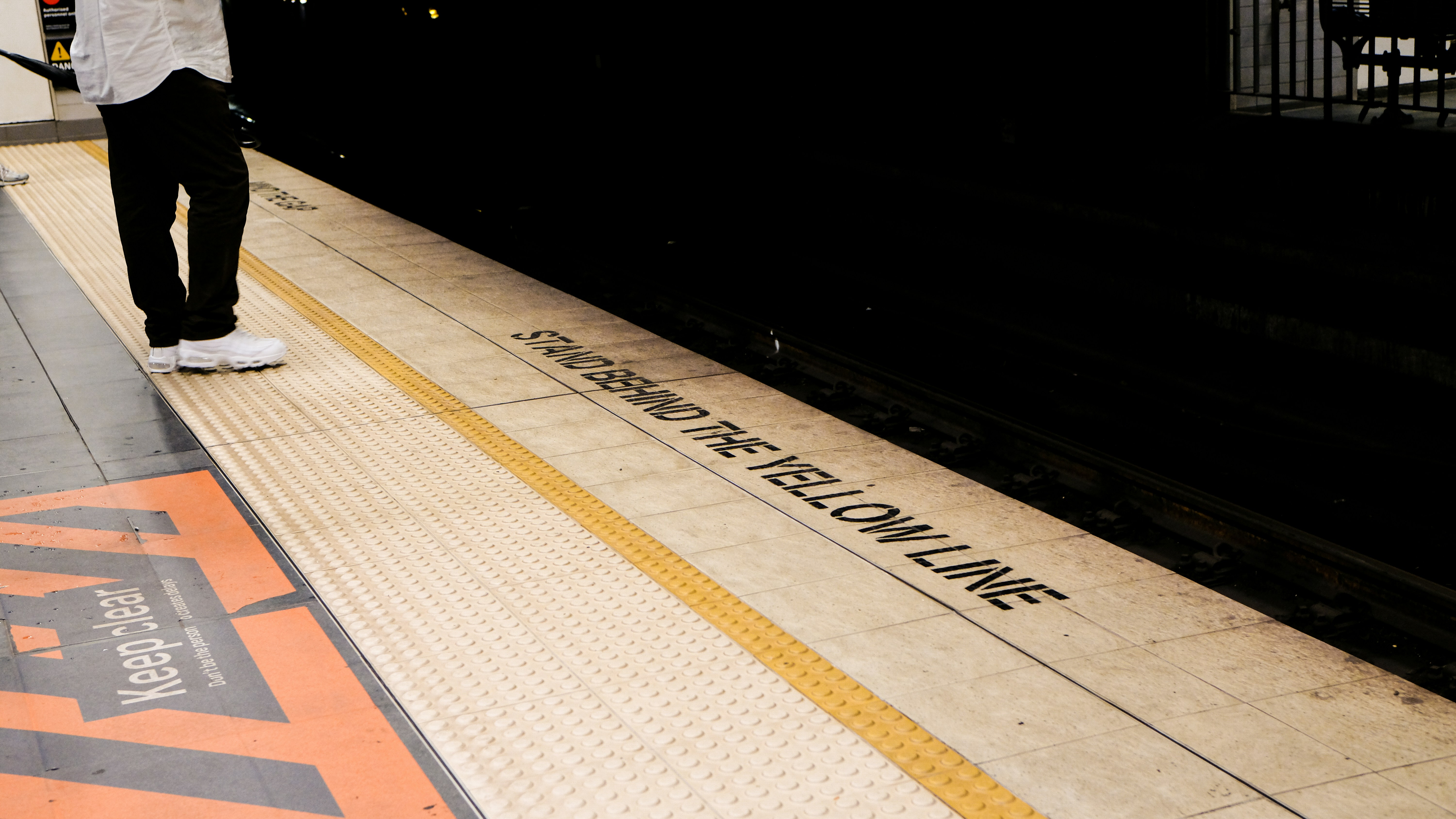 Pessoa parada atrás da linha amarela em uma plataforma.
