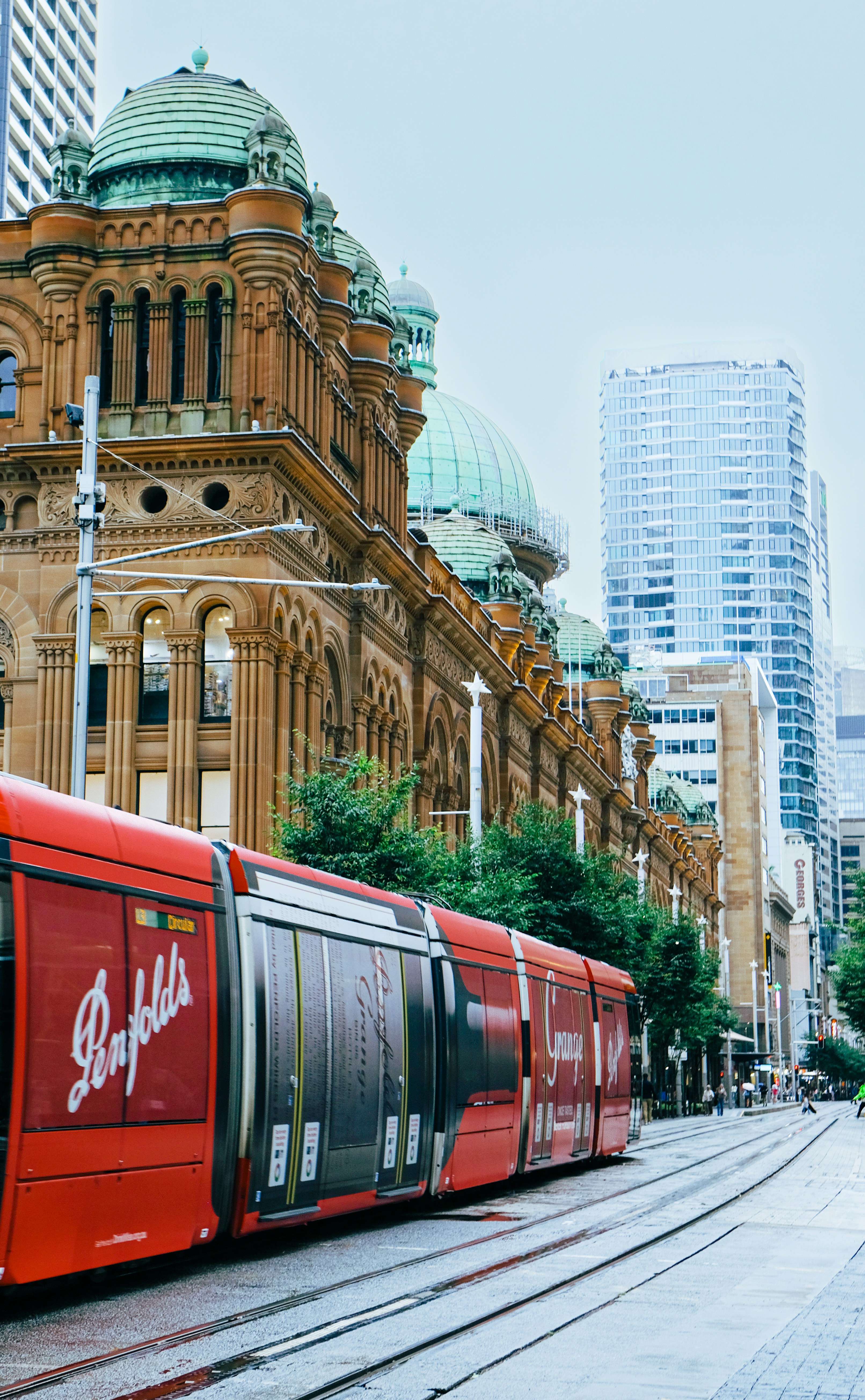 Um bonde vermelho passa por prédios históricos em uma cidade.