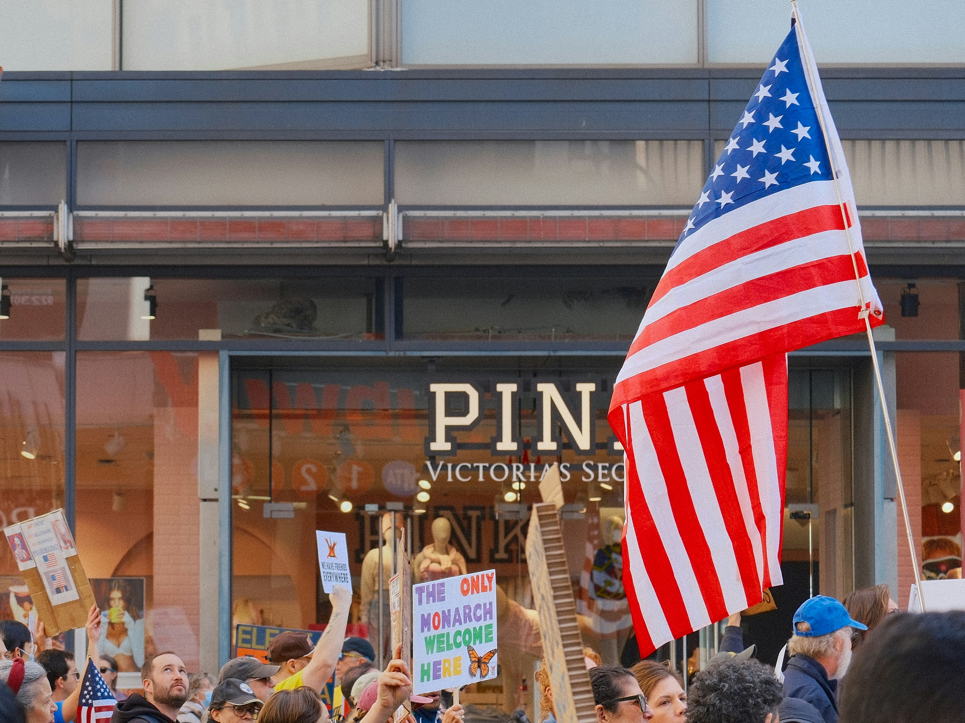 American flag waves at a protest outside a store.