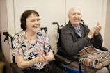 Elderly couple clapping in wheelchairs
