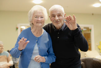 Elderly couple waving hello in a room