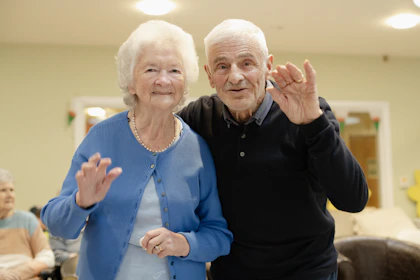 Elderly couple waving hello in a room
