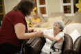 Caregiver assists elderly woman with walker.