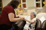 Caregiver assists elderly woman with walker.