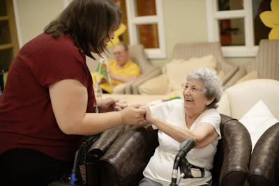 Caregiver assists elderly woman with walker.
