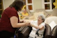 Caregiver assists elderly woman with walker.