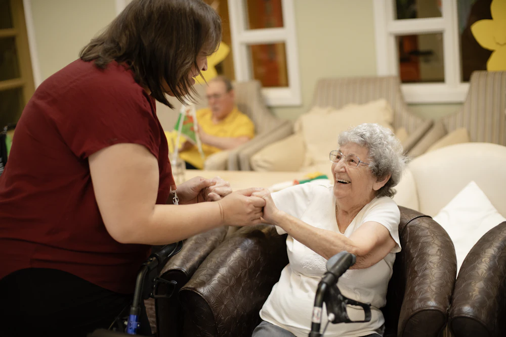 A caregiver gently assisting a senior woman walking with her walker