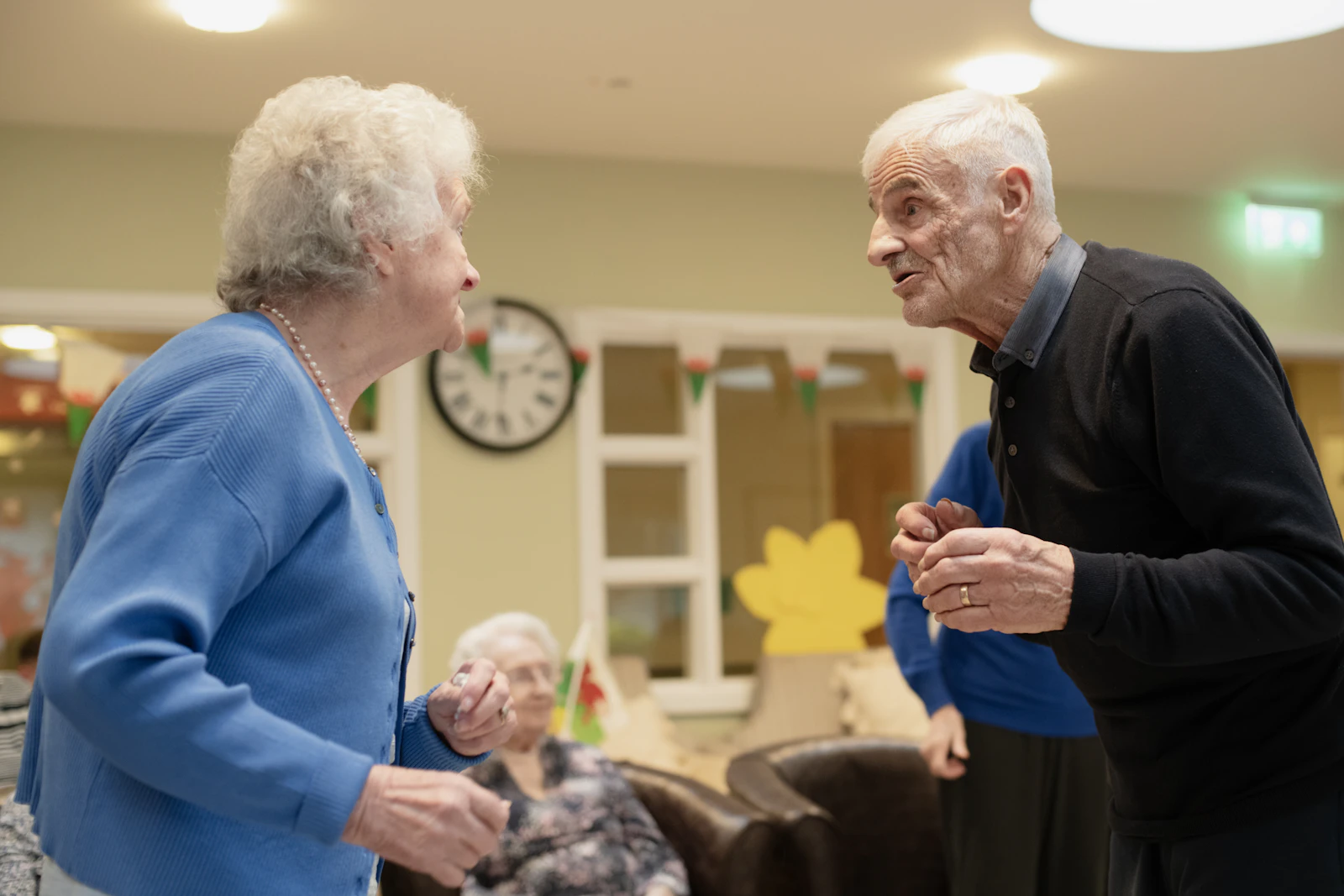 An elderly couple in conversation in a warmly lit room