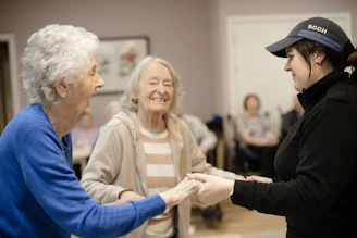 Two elderly women holding hands with a younger woman
