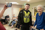 Police officer poses for a photo with an elderly woman.