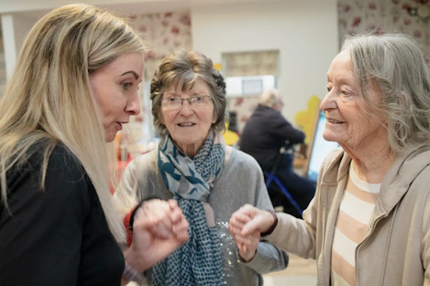 Three women interacting indoors with soft lighting.
