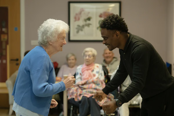 A senior woman joyfully dancing with a younger caregiver
