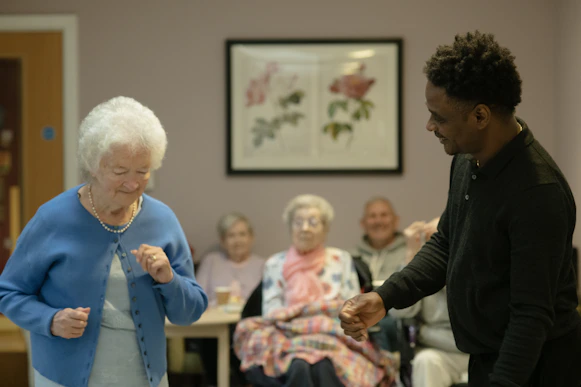 Elderly woman dancing with a man in a room.