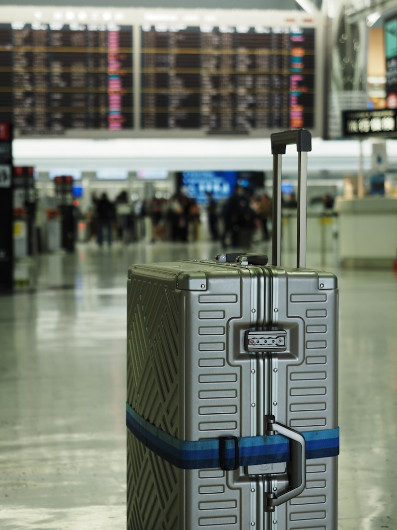 Silver suitcase with blue strap in airport terminal
