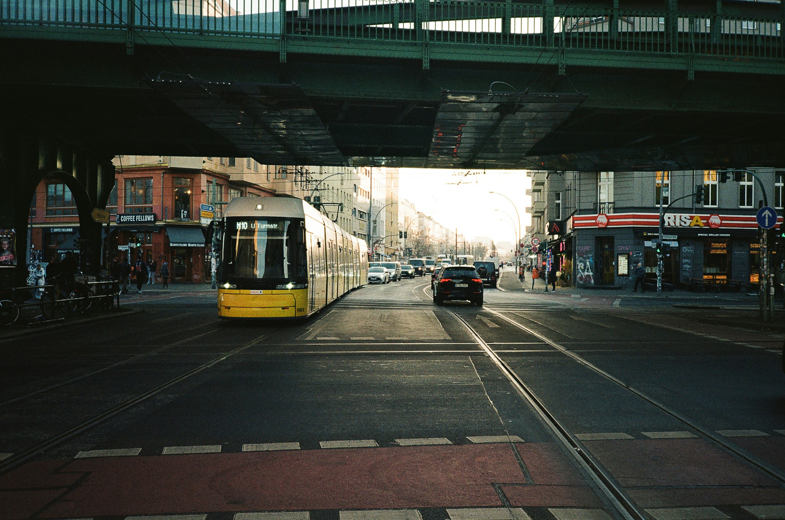 Un tram giallo e un'auto su una strada cittadina.