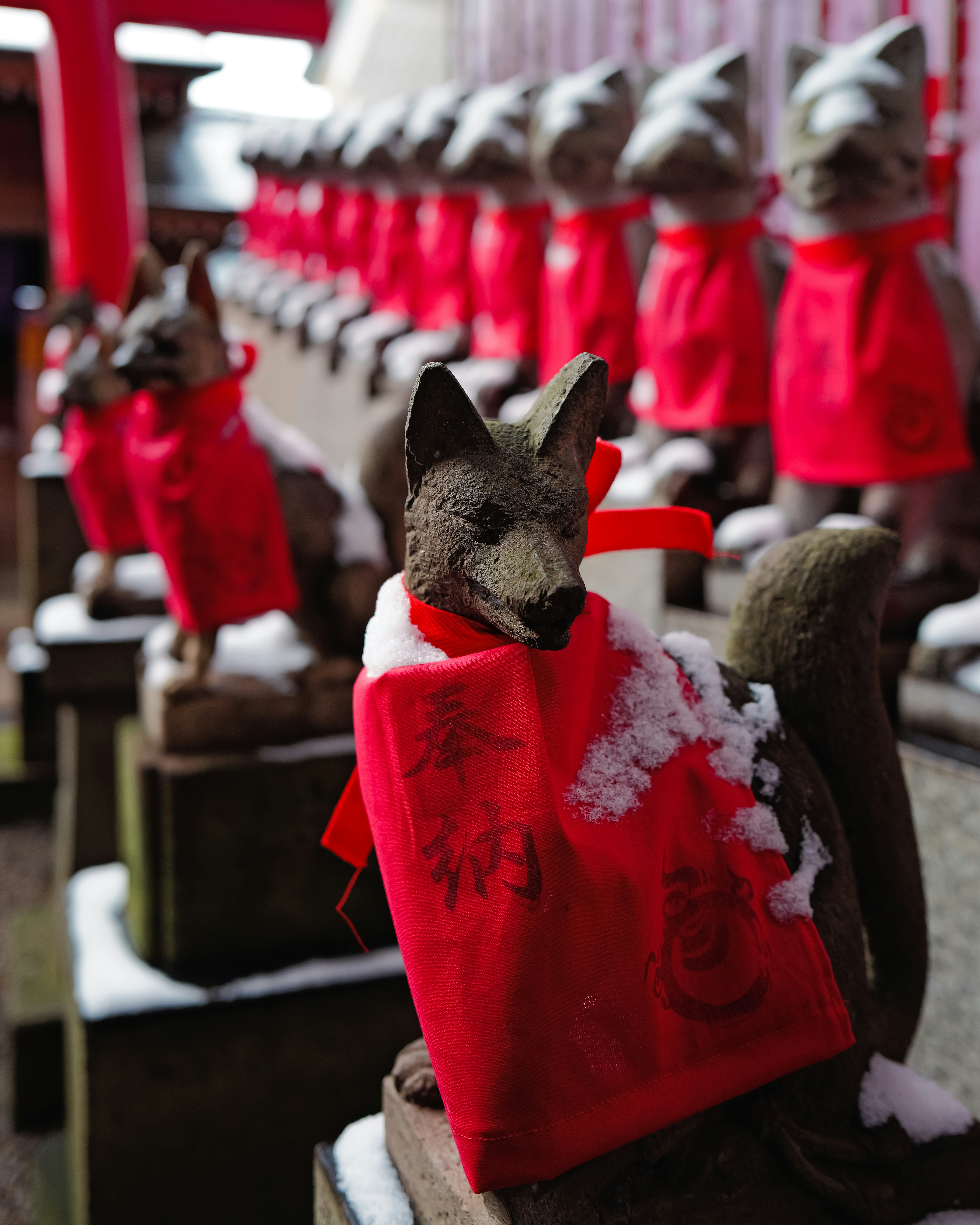 Stone fox statues wearing red bibs in snow