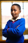 Young boy in a blue sweater with arms crossed