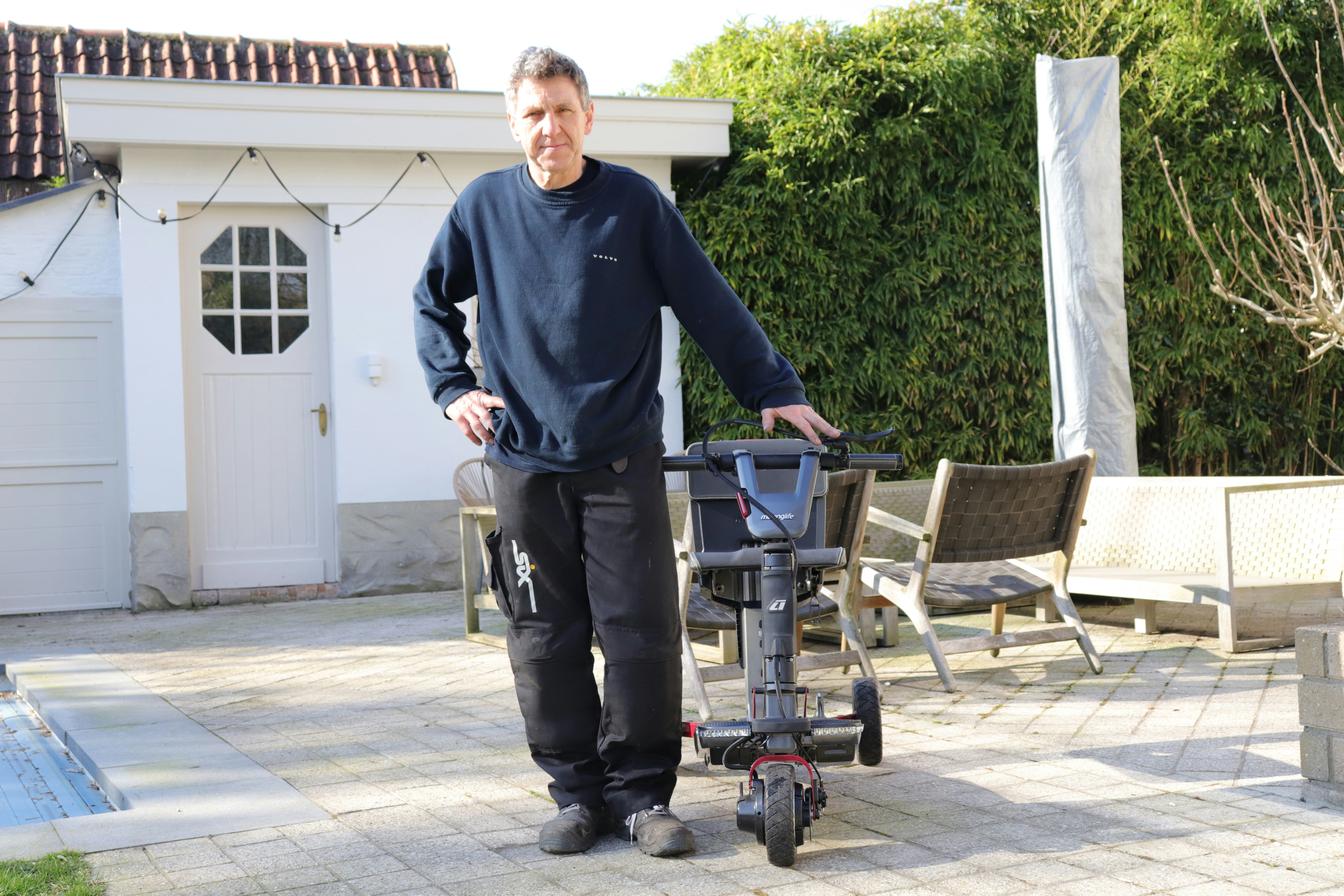 Man standing next to a mobility scooter outdoors