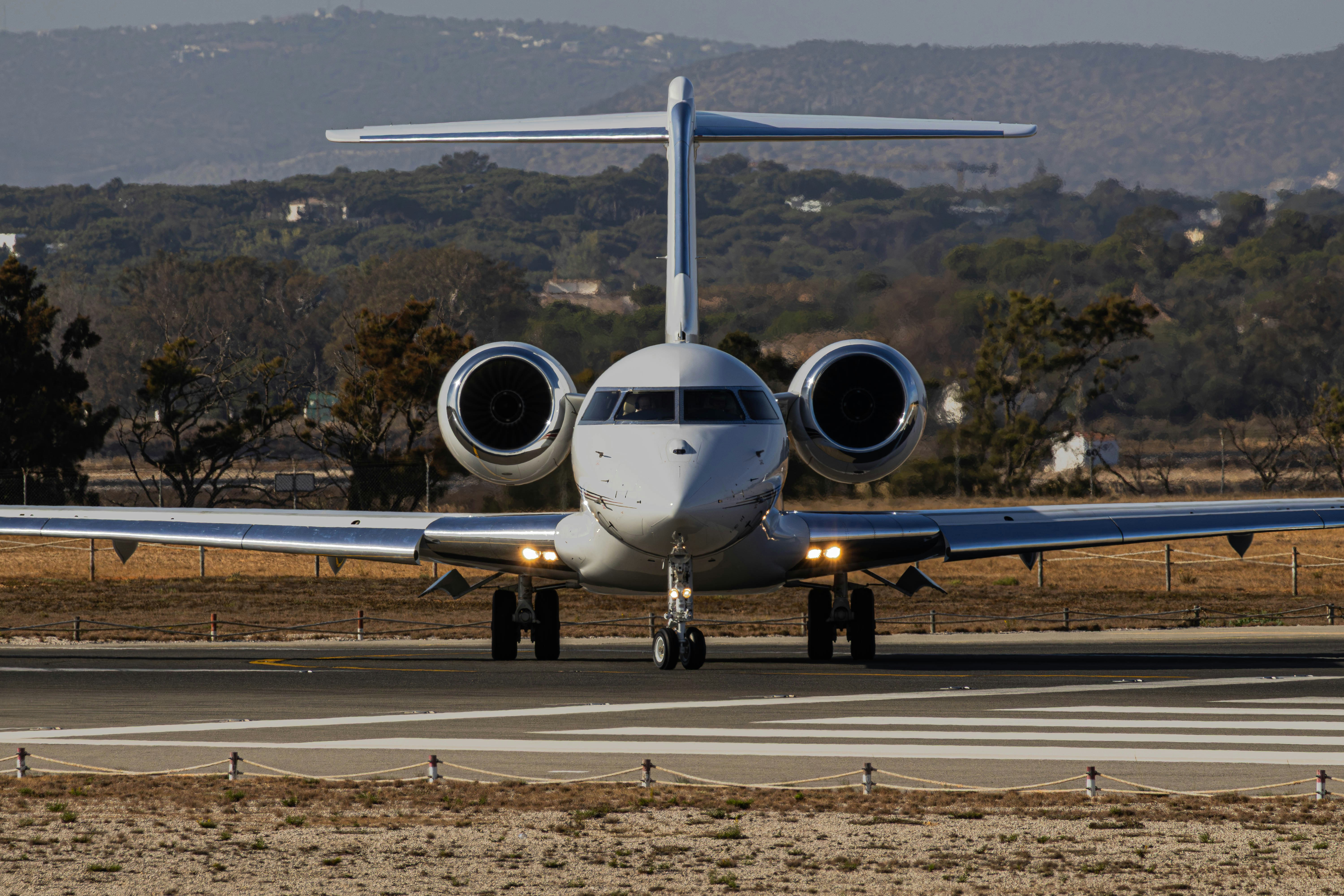 A white private jet taxiing on a runway
