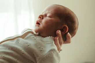 A newborn baby sleeps peacefully in someone's arms.