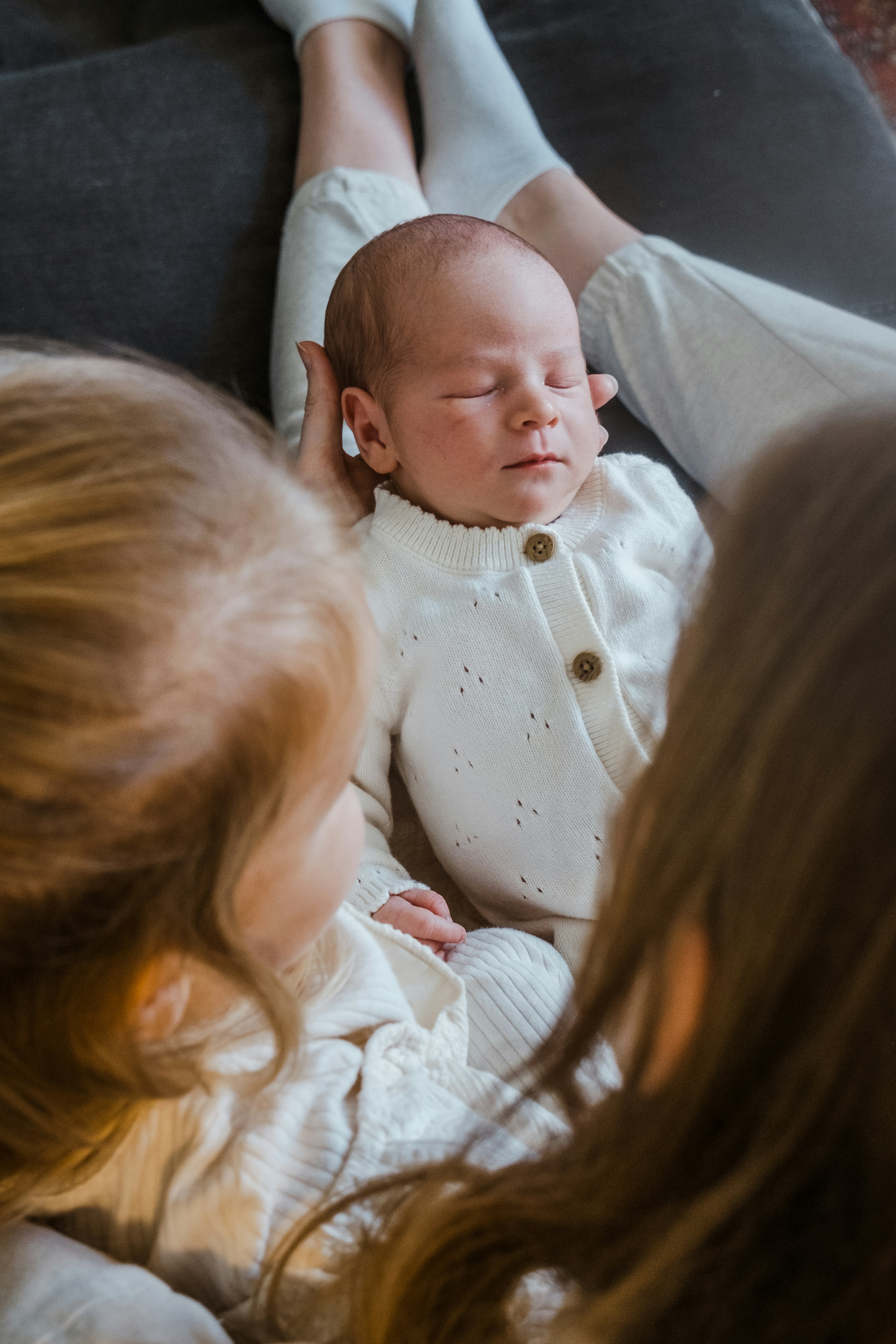 Newborn baby rests between two sisters