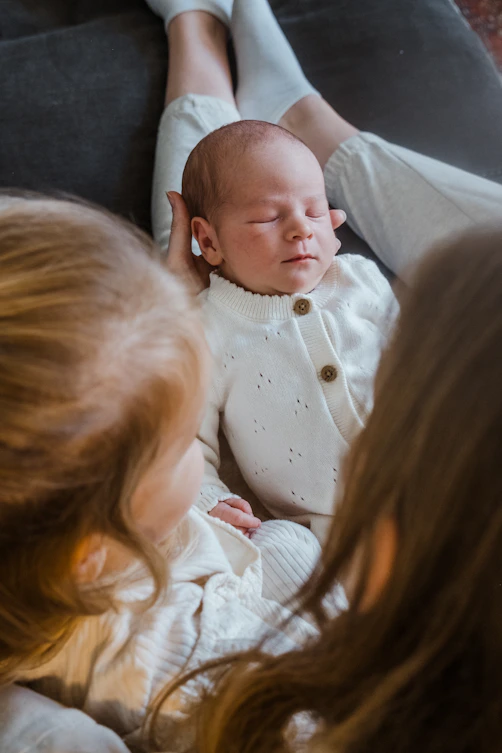 Newborn baby rests between two sisters
