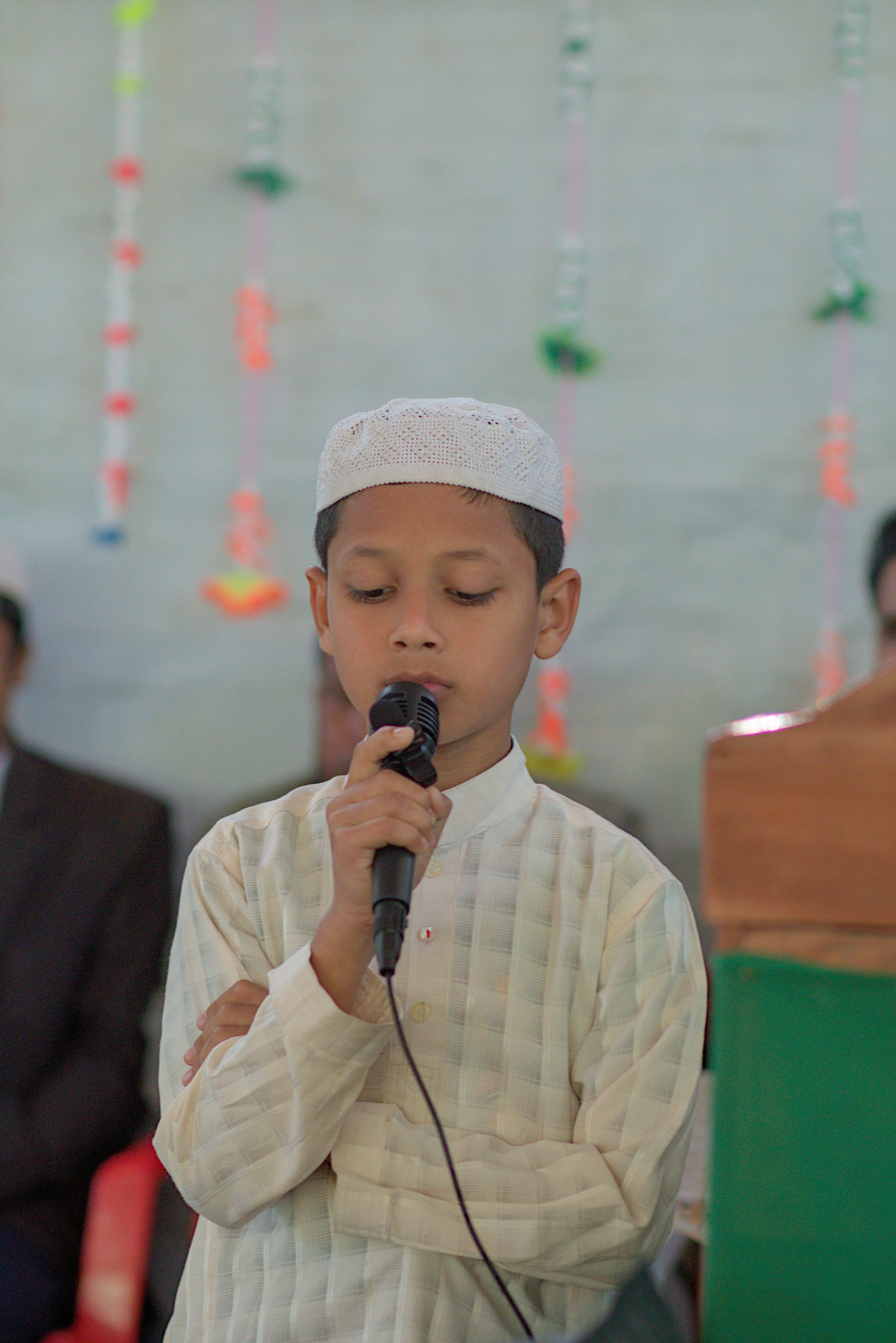 Young boy speaking into a microphone wearing a cap