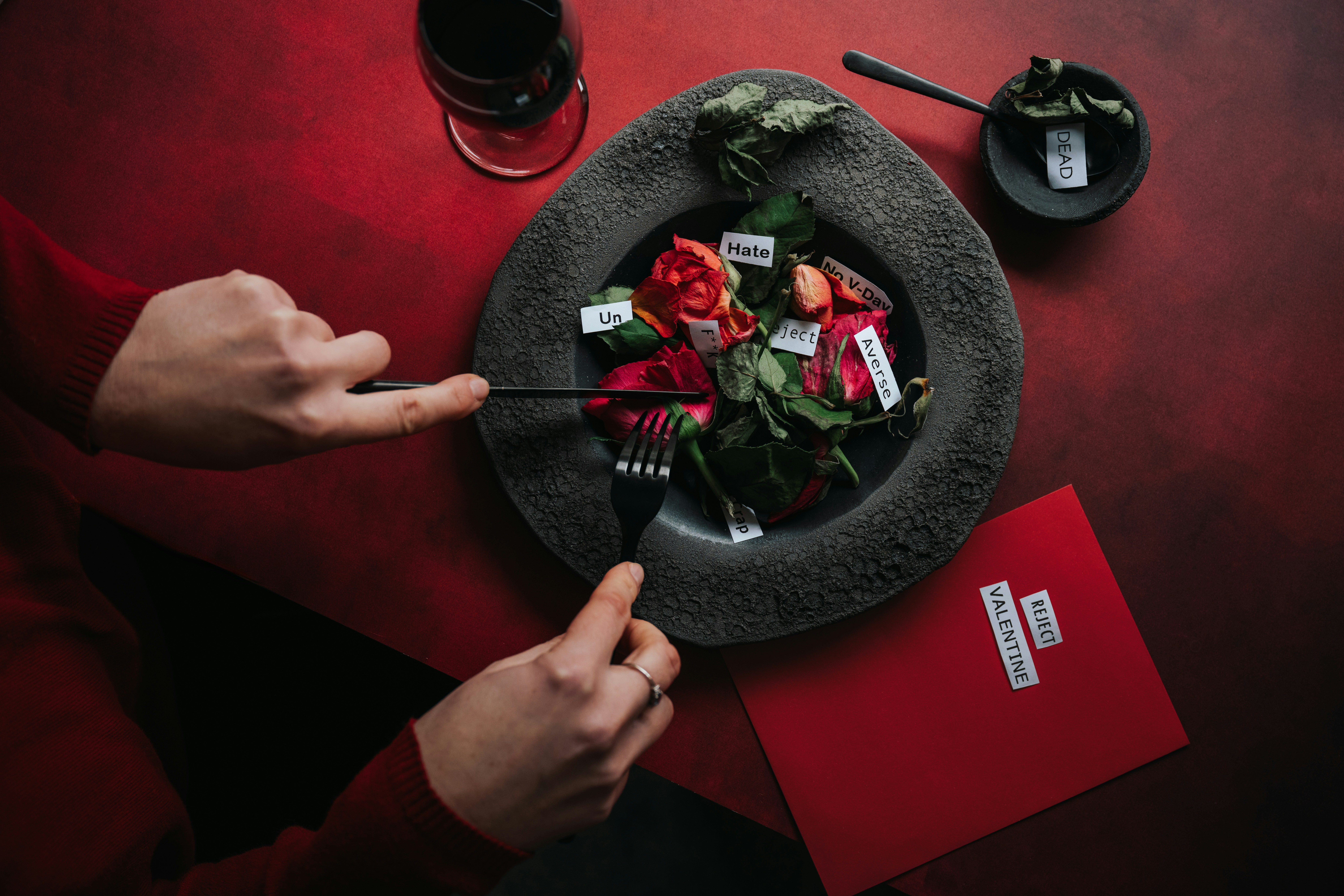 Une personne coupant des fleurs avec des notes sur une table rouge.