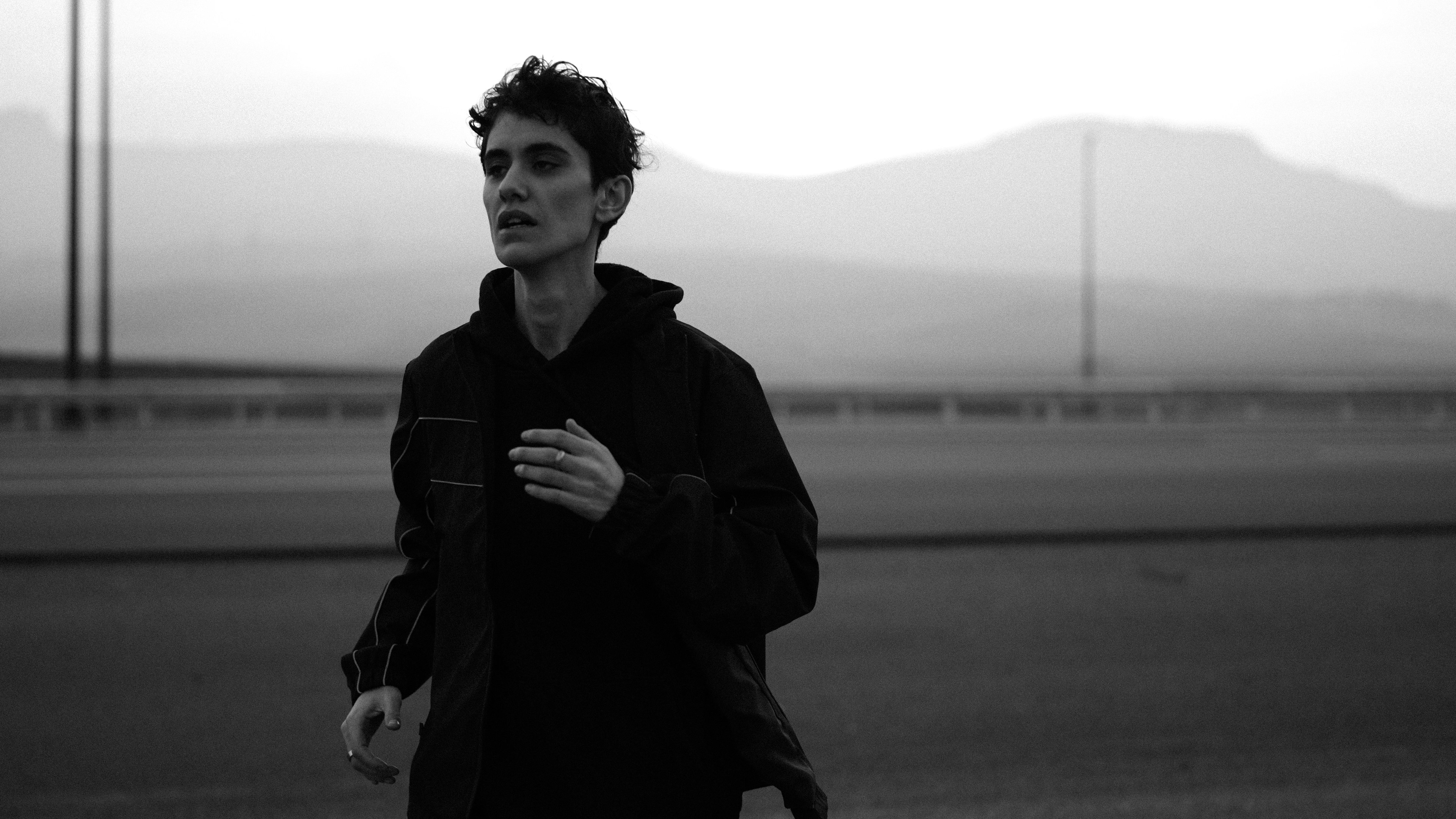 Young man running outdoors in black hoodie
