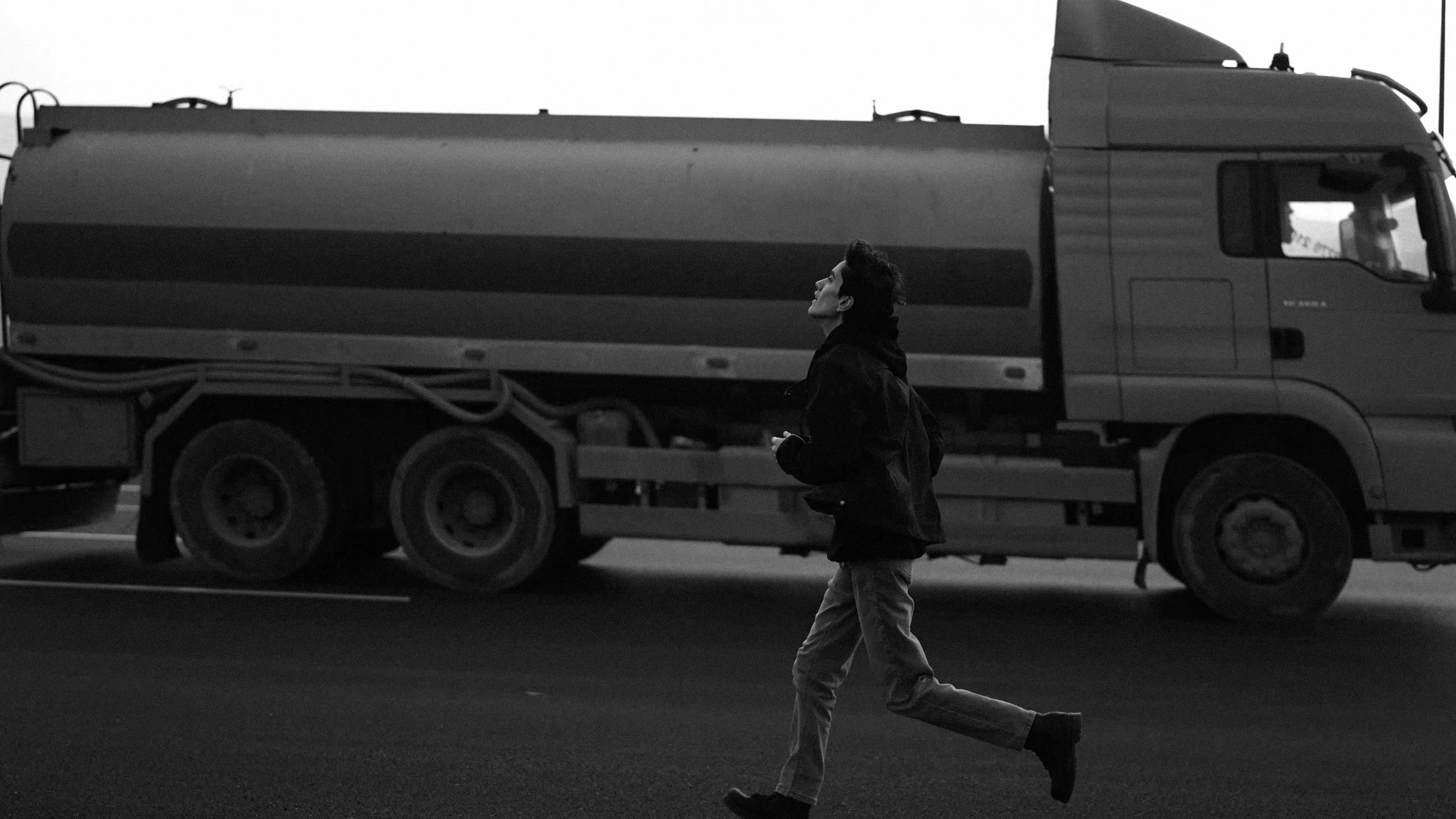 Person running in front of large tanker truck