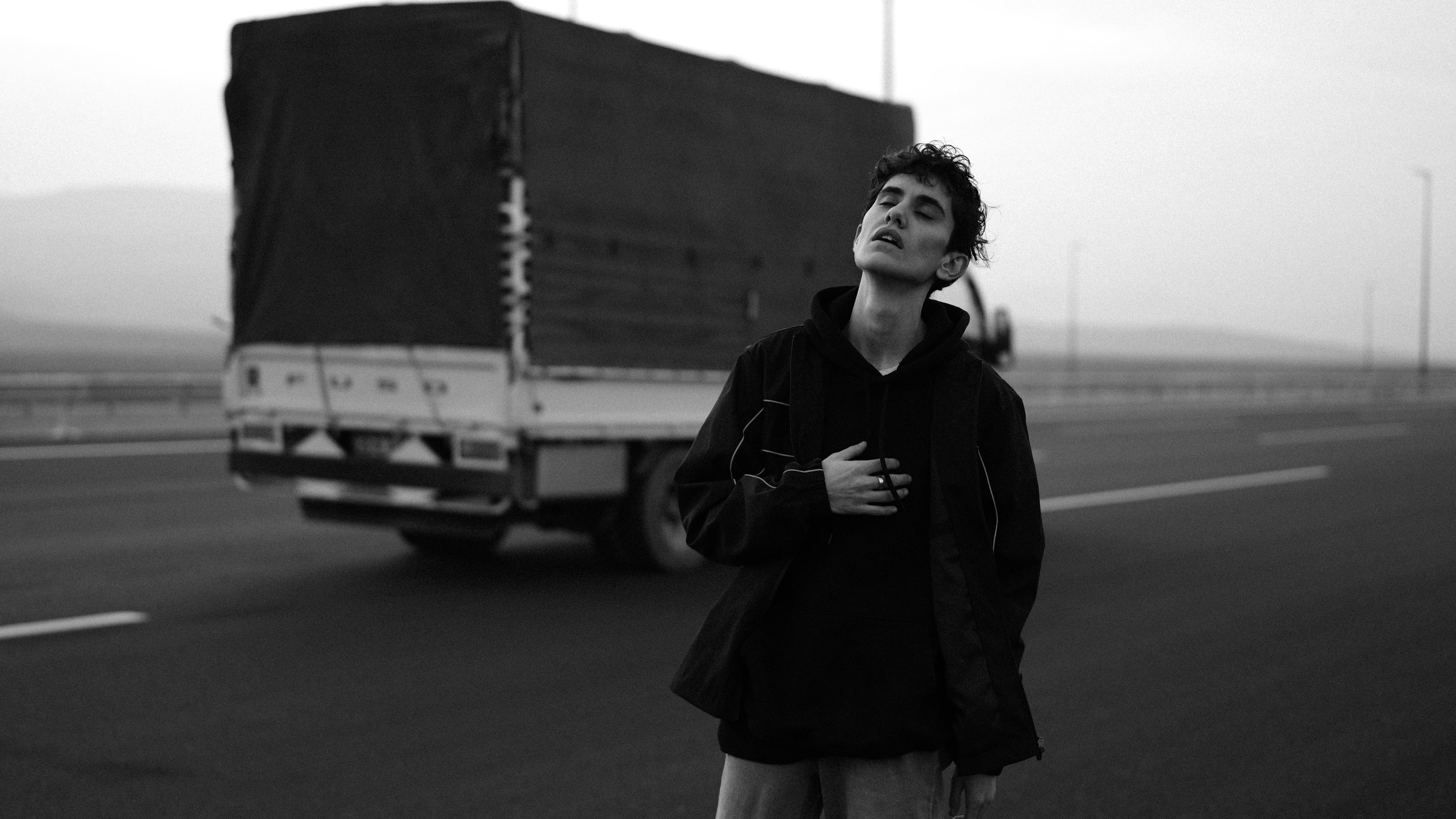 Giovane in piedi sulla strada, camion dietro di sé