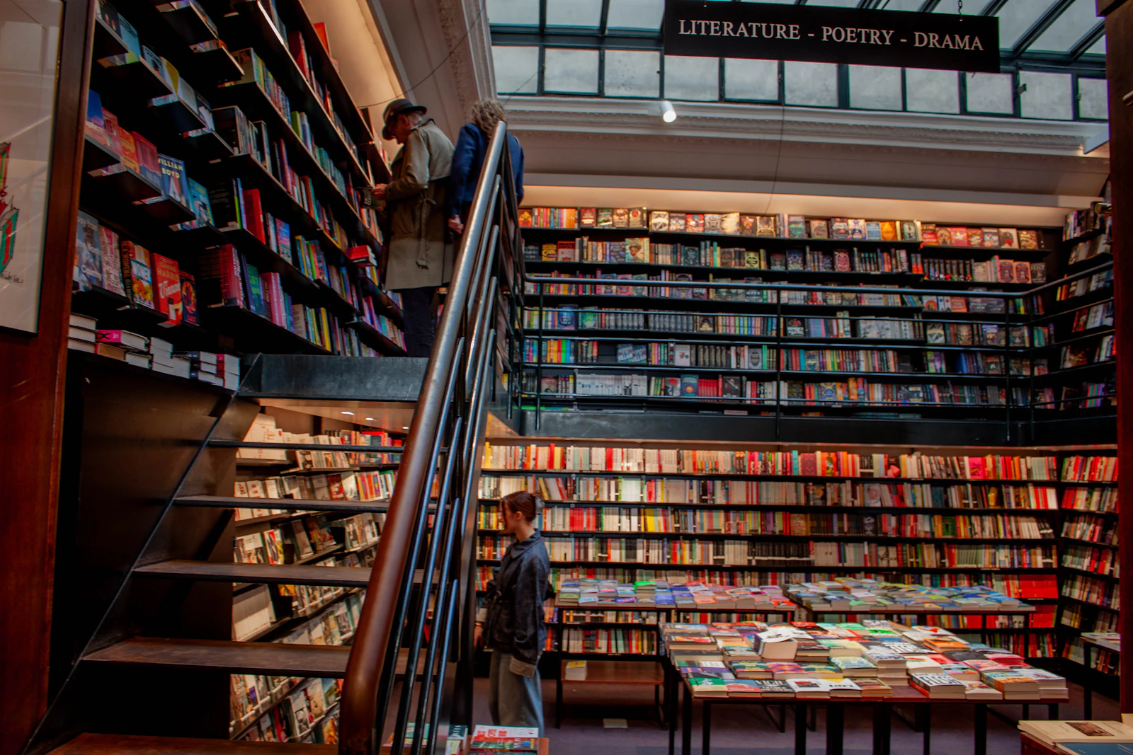 Personas recorriendo una librería real entre estanterías llenas de libros